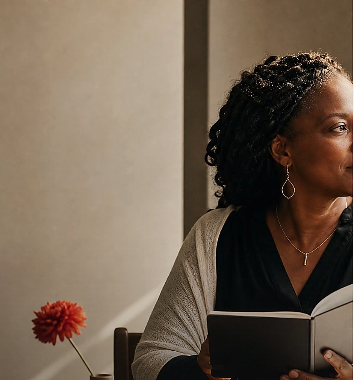 Woman reflecting over a notebook and financial papers in warm natural light